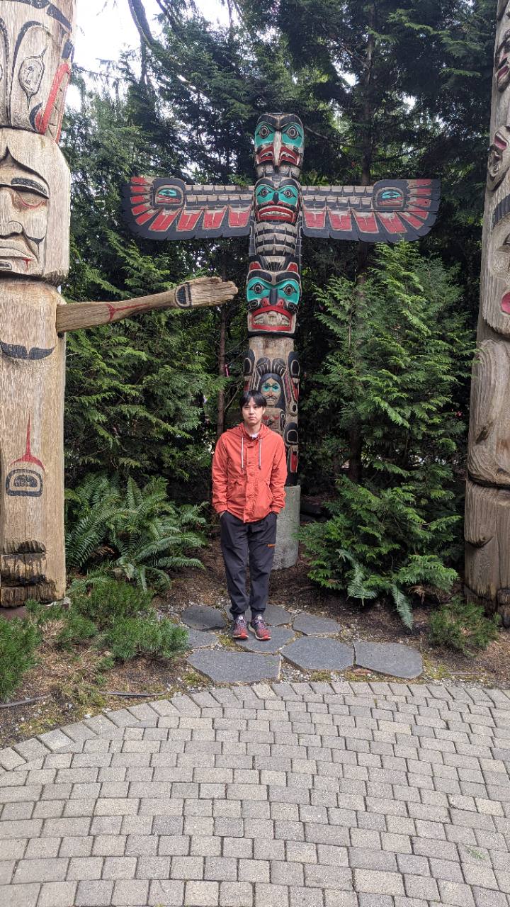 Your travel portrait standing beside carved poles in the forest